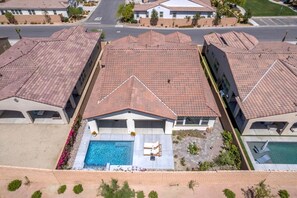 Et boligområde med huse, rødlægte tag, et centralt beliggende pool og parkeringsplads.