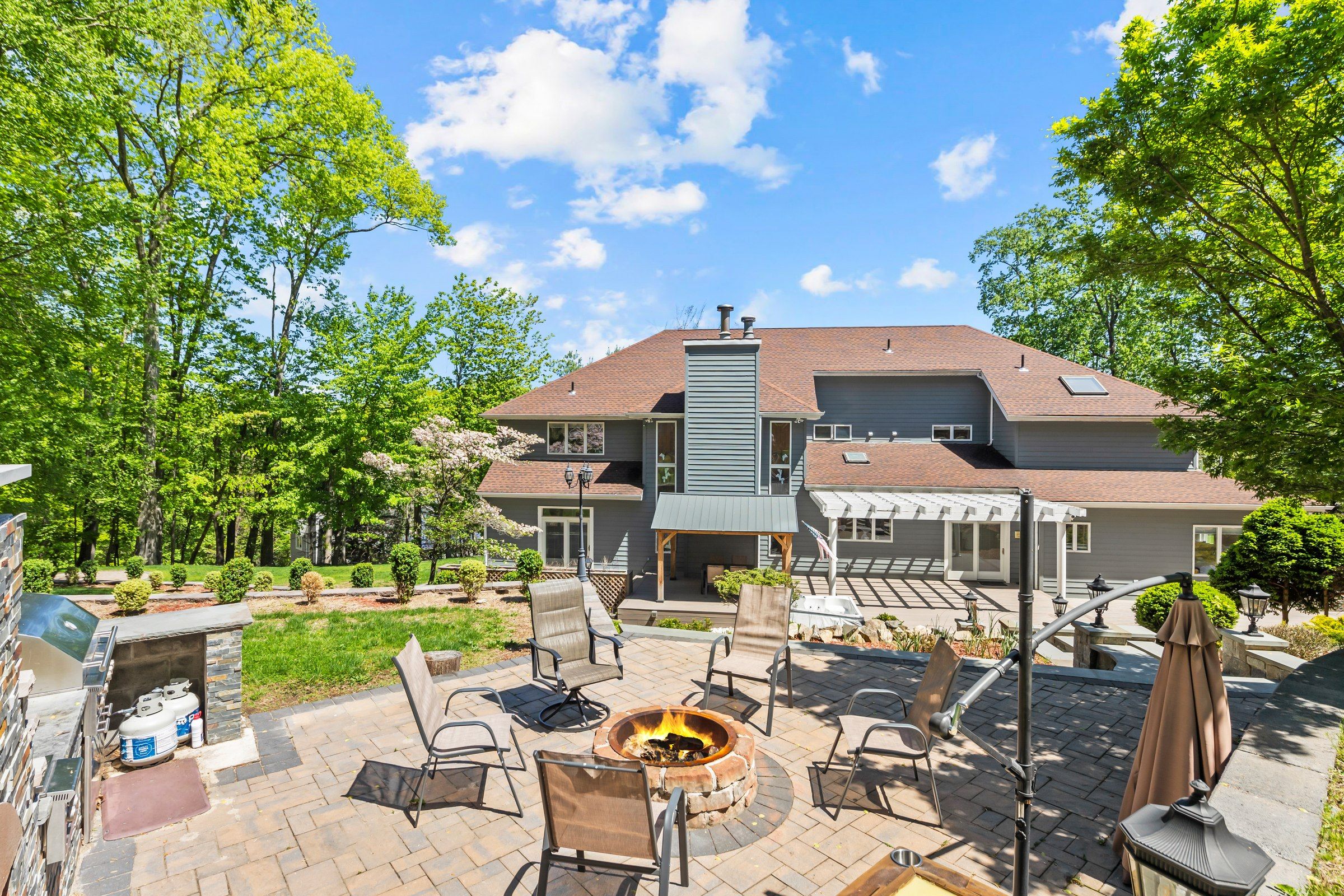 A residential property with a patio area featuring outdoor furniture, a fire pit, and a barbecue grill.