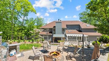 A residential property with a patio area featuring outdoor furniture, a fire pit, and a barbecue grill.