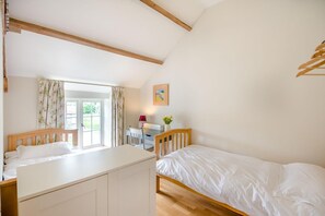 A bedroom with a wooden bed, a desk with a chair, a window with curtains, and a radiator. - 2 Bed in York (oc-y008) (Gilling East)