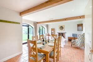 A dining area with a wooden table set for four, surrounded by chairs, with a fireplace and a television in the background. - 2 Bed in York (oc-y008) (Gilling East)