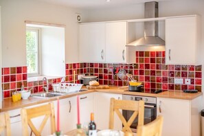 A modern kitchen with a central island, a window, and red-tiled backsplash. - 2 Bed in York (oc-y008) (Gilling East)