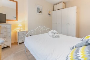 Un dormitorio con cama, cómoda, espejo y armario.