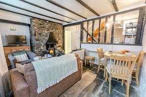 Una sala de estar acogedora con chimenea de piedra, un televisor y un comedor con muebles de madera.