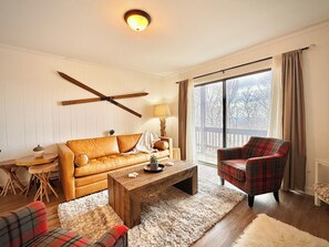 A living room with a sofa, a plaid armchair, a coffee table, and a lamp. - Renovated 2BR Mountain View Condo ½ Mile to Beech Mtn Resort (Beech Mountain)