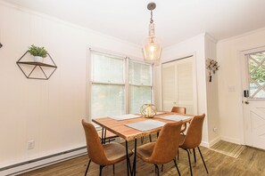 A dining area with a wooden table, four chairs, and a hanging light fixture. - Renovated 2BR Mountain View Condo ½ Mile to Beech Mtn Resort (Beech Mountain)
