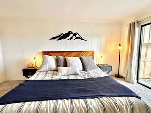 A bedroom with a bed, bedside tables, a wall-mounted artwork, and a floor lamp. - Renovated 2BR Mountain View Condo ½ Mile to Beech Mtn Resort (Beech Mountain)