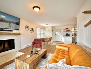 A living room with a fireplace, a sofa, a coffee table, and a television. - Renovated 2BR Mountain View Condo ½ Mile to Beech Mtn Resort (Beech Mountain)