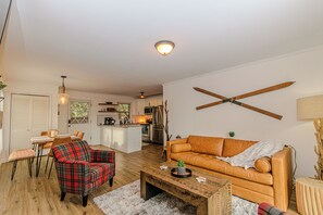 Ein Wohnzimmer mit einer Couch, einem karierten Sessel, einem Couchtisch und einem Essbereich mit Tisch und Stühlen.