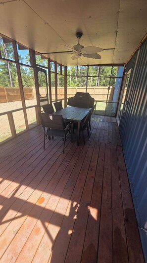 Un patio esterno coperto con tavolo e sedie, una ventola a soffitto e vista sulla zona circostante.