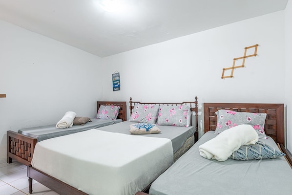 A bedroom with three single beds, each with a wooden headboard and grey bedding.