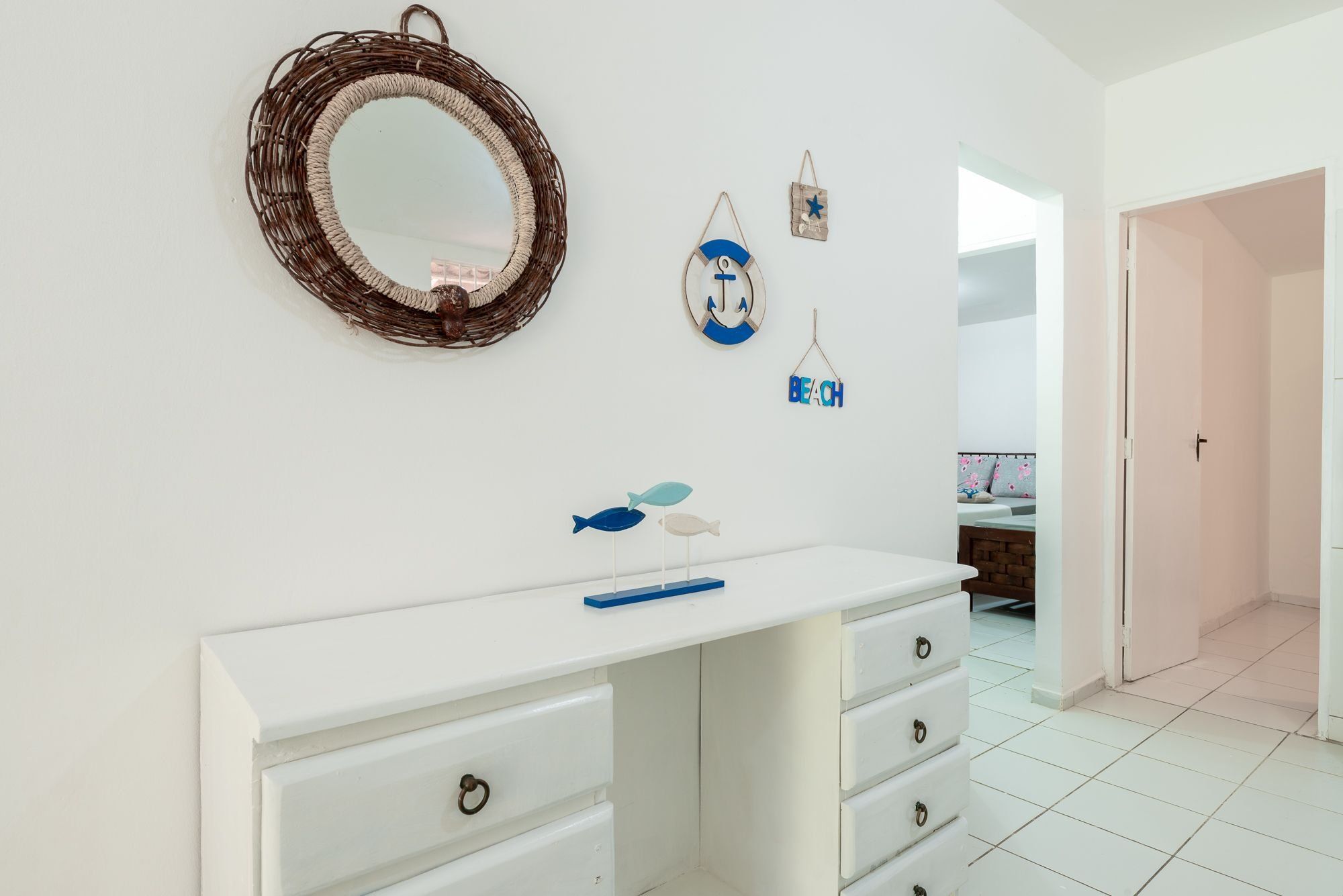 Une salle de bain avec un meuble-lavabo blanc, un miroir et des éléments de décoration murale, dont un panneau sur le thème de la plage.