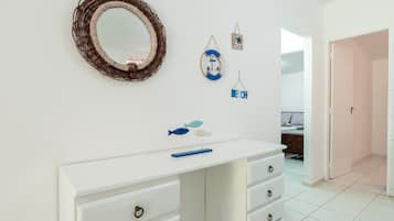 Une salle de bain avec un meuble-lavabo blanc, un miroir et des éléments de décoration murale, dont un panneau sur le thème de la plage.