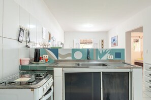 A kitchen with a gas stove, a sink, and a window with a view of the outside.