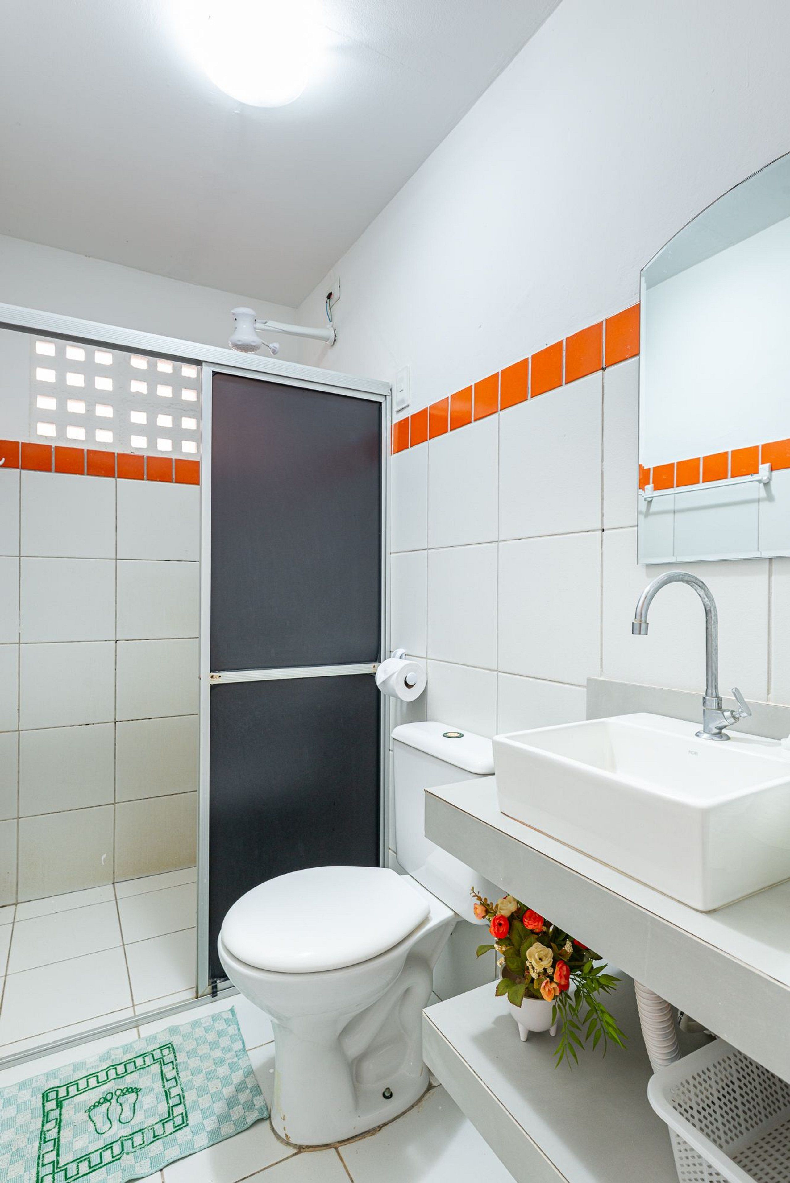 Une salle de bain équipée de toilettes, d’un lavabo, d’une douche et d’un miroir.