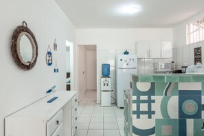 A kitchen with white cabinets, a microwave, a water dispenser, and a patterned backsplash.