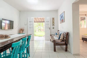 A dining area with a table and chairs, a television, and a view of the outdoors.
