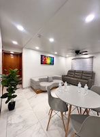Una sala de reuniones moderna con una mesa redonda, sillas grises, un sofá y un ventilador de techo.