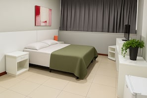 A bedroom with a bed, nightstand, bedside table, a potted plant, and a wall-mounted TV. - Blu Apart Hotel (Mogi Guaçu)