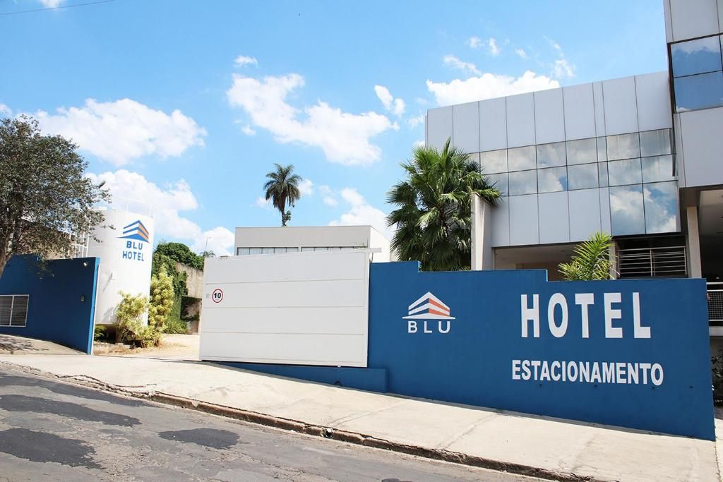 Een hotel ingang met een blauw bord waarop 'HOTEL ESTACIONAMENTO' staat en het logo van 'BLU HOTEL'.