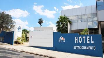 Een hotel ingang met een blauw bord waarop 'HOTEL ESTACIONAMENTO' staat en het logo van 'BLU HOTEL'.
