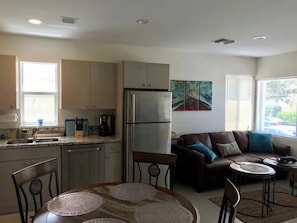 A compact living space with a kitchenette, a dining area with a round table, a sofa, and a small coffee table. - Ground-Floor APT 1BR 1BA | Coastal Retreat (Hollywood)