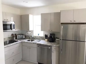 A modern kitchen with stainless steel appliances, a granite countertop, and white cabinetry. - Ground-Floor APT 1BR 1BA | Coastal Retreat (Hollywood)