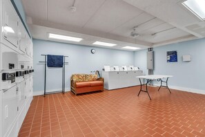 Una habitación con un sofá, una mesa, un reloj y una fila de lavadoras.