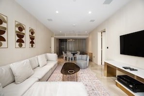 Een moderne woonkamer met een witte bank, een salontafel en een flatscreen televisie op een witte console.