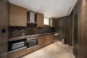 A modern kitchen with wooden cabinets, stainless steel appliances, and a herringbone-patterned floor. - Modern 2BR Gem | Prime Palm Jumeirah Location (Dubai)