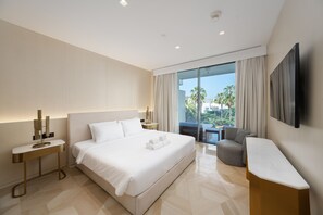A modern hotel room with a large bed, a seating area with a view, and a flat-screen TV mounted on the wall. - Modern 2BR Gem | Prime Palm Jumeirah Location (Dubai)
