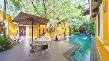 Un espace aménagé au bord de la piscine, avec une table et des chaises, un escalier et une petite piscine.