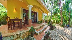 A covered outdoor seating area with a table and chairs, surrounded by lush greenery and a tiled floor. - A charming villa with access to Yalku Lagoon (Akumal)