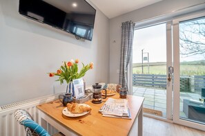 A dining area with a table set for breakfast, including croissants, a coffee pot, and tulips. - 1 Bed in Gatehouse Of Fleet (oc-t34445) (Gatehouse of Fleet)