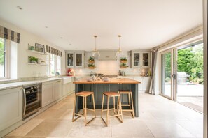 A modern kitchen with a central island, bar stools, and a sliding glass door leading to an outdoor area.
