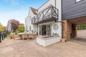 A two-story house with a balcony, a patio with outdoor furniture, and a garage.