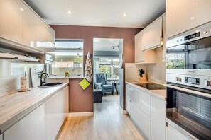 A modern kitchen with a central island, a built-in oven, and a view into the living area. - 2 Bed in Freuchie (oc-h34757) (Freuchie)