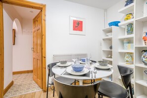 A dining area with a round table, chairs, and a variety of bowls and plates. - 2 Bed in Swanage (oc-t35179) (Swanage)