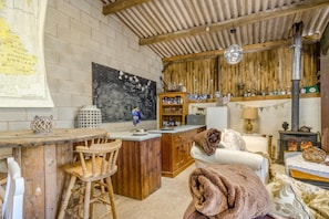 A rustic interior with a wooden bar, a chalkboard menu, and a stone fireplace.