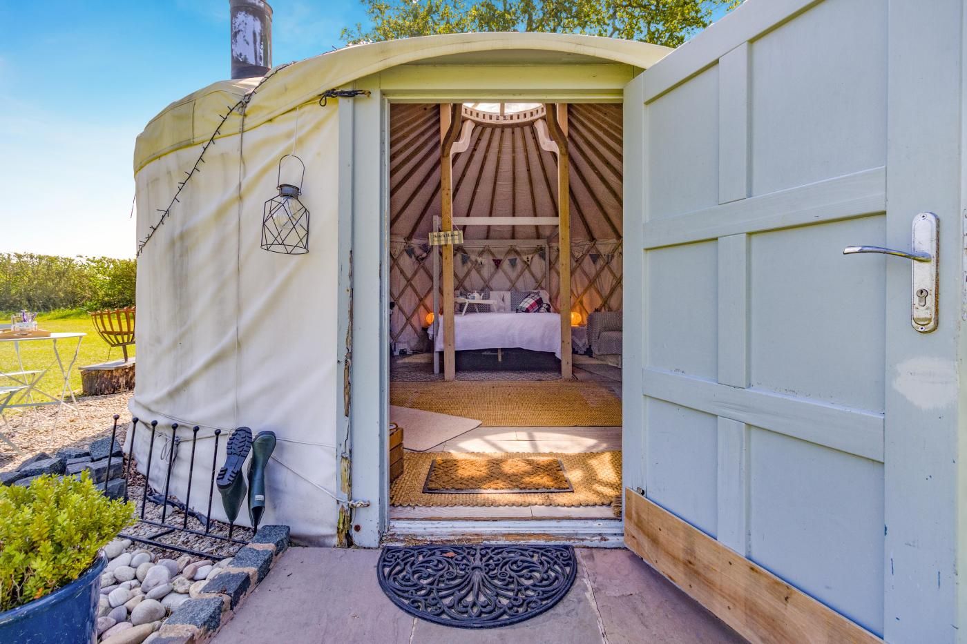 A yurt with a bed, a lantern, and a small table.