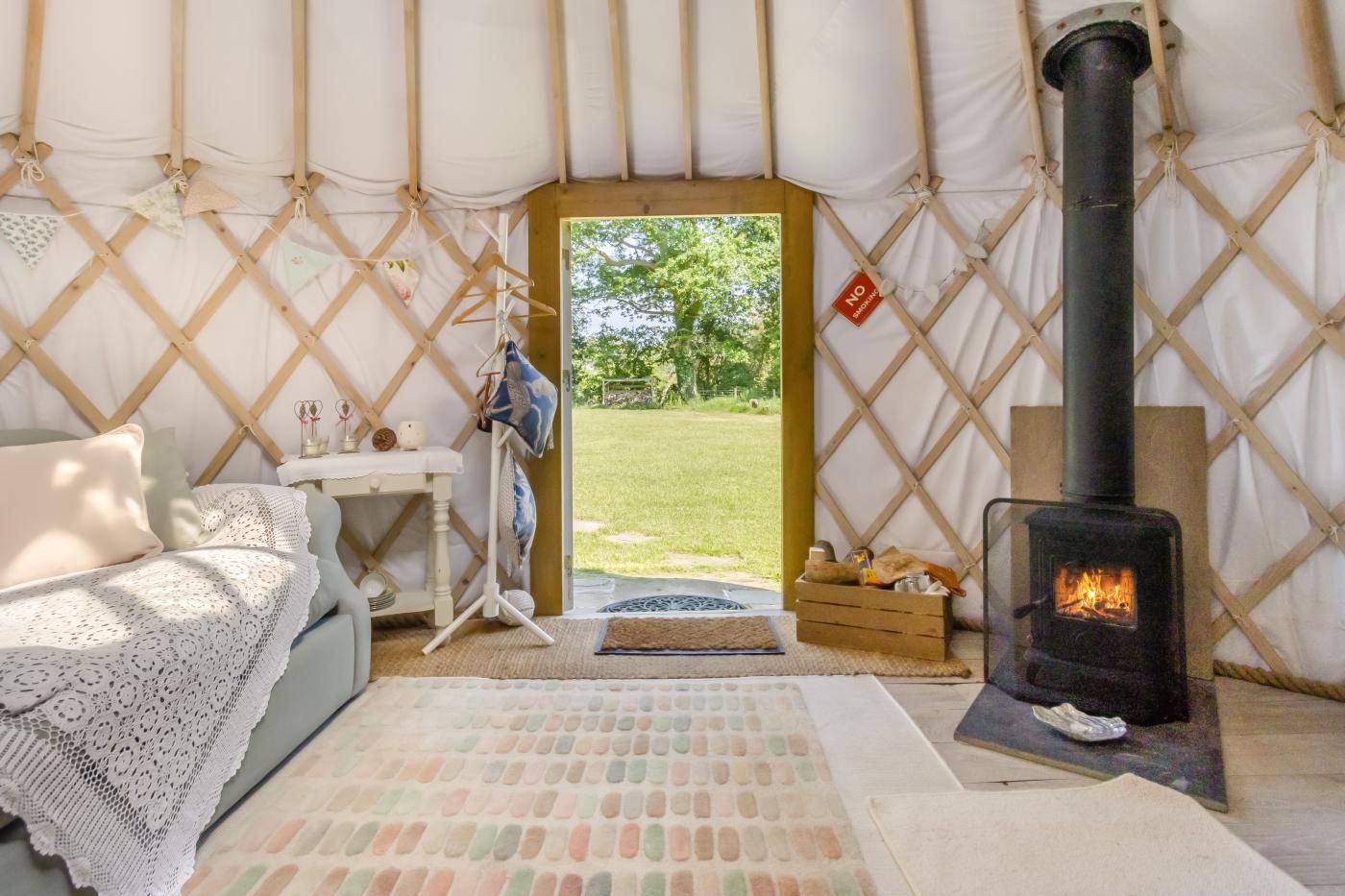 L’intérieur accueillant d’une tente, avec un lit, une petite table, un porte-vêtements suspendu et un poêle à bois.