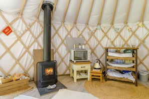A cozy room with a wood-burning stove, a small table with a kettle, and a shelf with folded towels. - 1 Bed in Bronington (oc-g39074) (Bronington)
