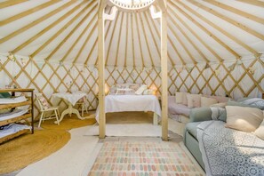 A cozy, well-lit tent with a bed, seating area, and a small table. - 1 Bed in Bronington (oc-g39074) (Bronington)