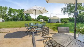 An outdoor patio with a table and chairs, a large umbrella, and a wooden deck.