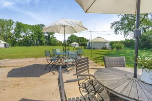An outdoor patio with a table and chairs, a large umbrella, and a wooden deck.