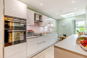 A modern kitchen with built-in appliances, a large window, and a view of greenery outside. - 2 Bed in Portinscale (oc-lr184) (Portinscale)