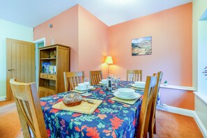 A dining room with a table set for four, a lamp, and a bookshelf. - 2 Bed in Portinscale (oc-lr184) (Portinscale)
