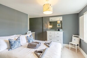 A bedroom with a bed, bedside tables, a dresser, a mirror, and a window with shutters. - 2 Bed in Fowey (oc-s42445) (Fowey)