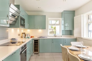 Une cuisine moderne avec des meubles de couleur turquoise, un four encastré et une fenêtre qui laisse entrer la lumière naturelle.