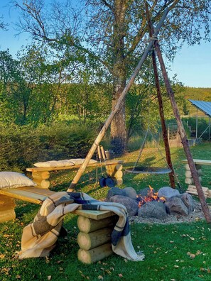 A rustic outdoor setting with a wooden swing, a fire pit, and a picnic table. - Rural retreat by meadows and forest in Holsbybrunn (Holsbybrunn)